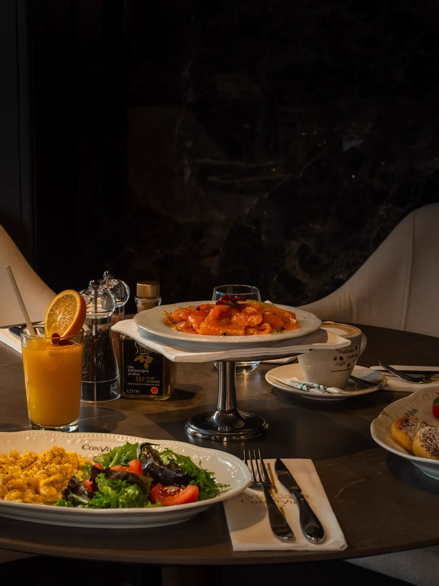 Breakfast table with scrambled eggs, smoked salmon, fresh orange juice and a cappuccino.