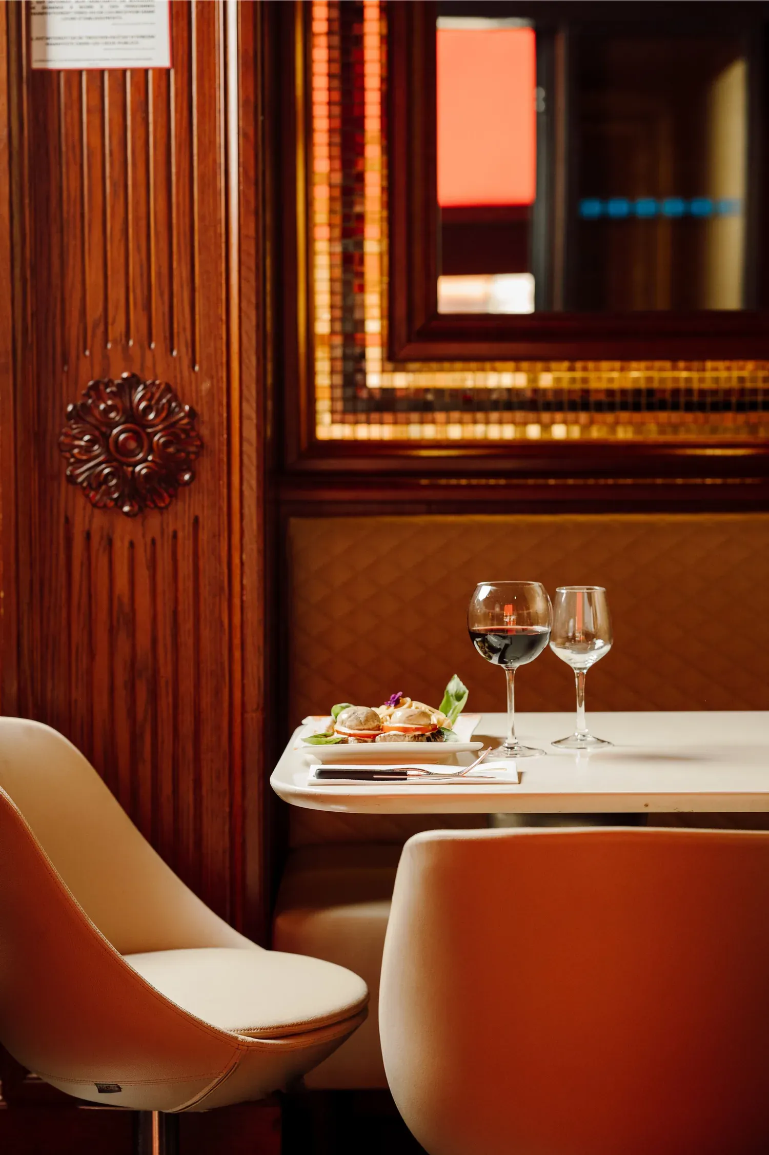 A quiet corner table with an antipasto and red wine, framed by mahogany panelling