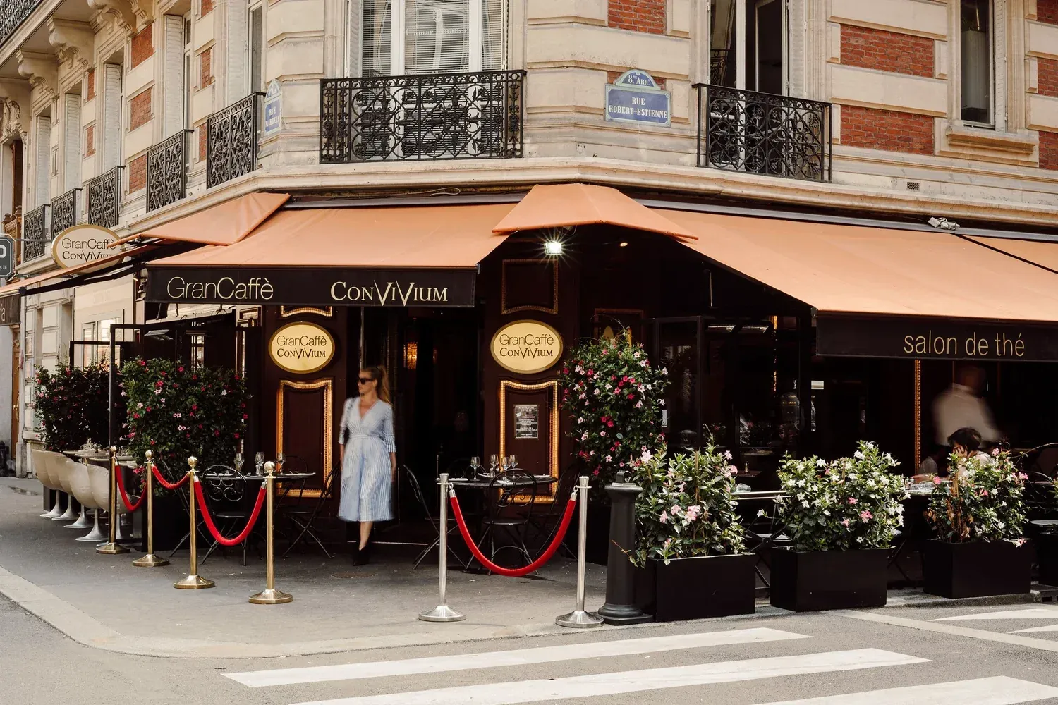 The Gran Caffè Convivium corner on Rue Marbeuf by day, terrace set beneath apricot awnings
