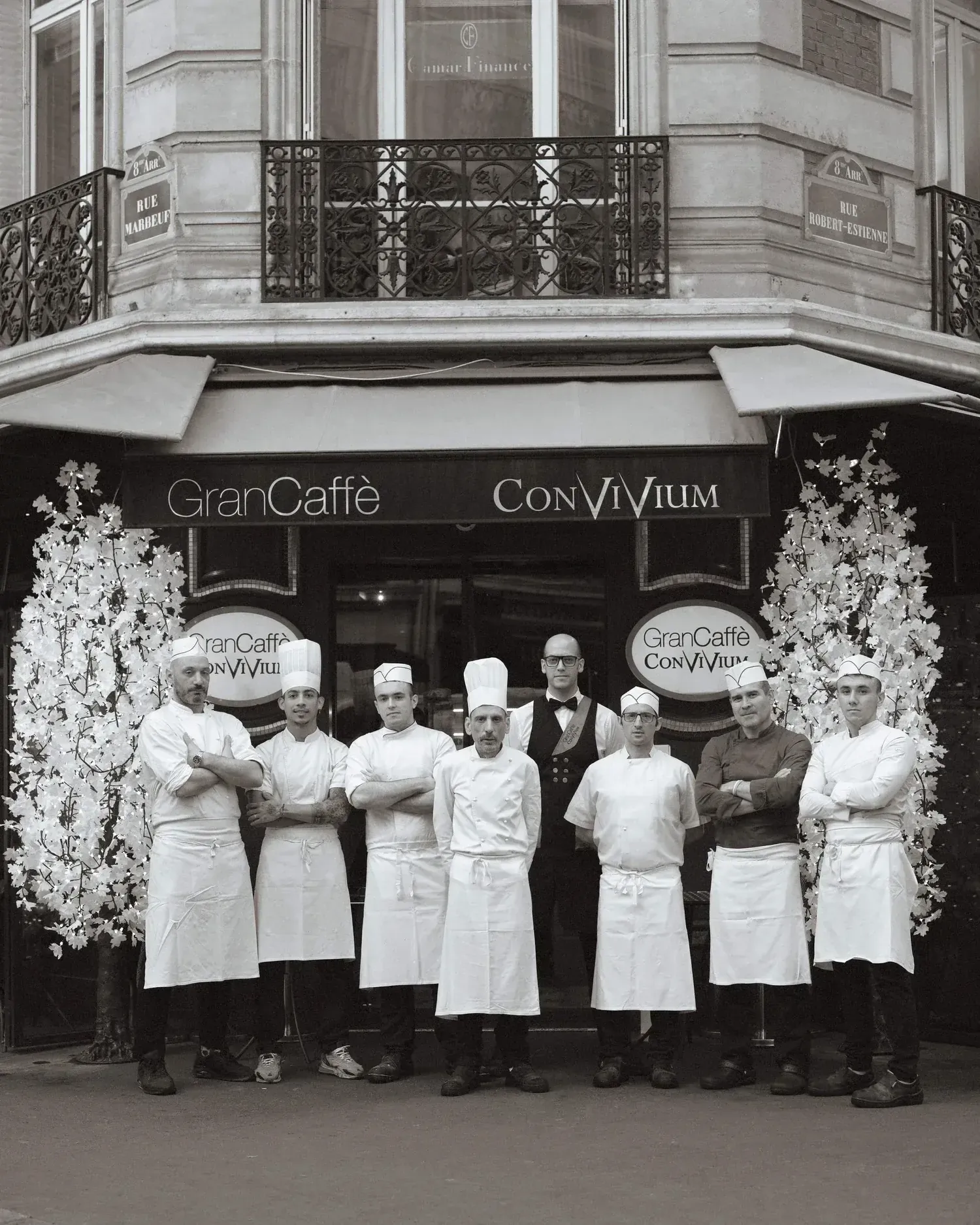 The kitchen brigade in whites, photographed in black and white outside the entrance