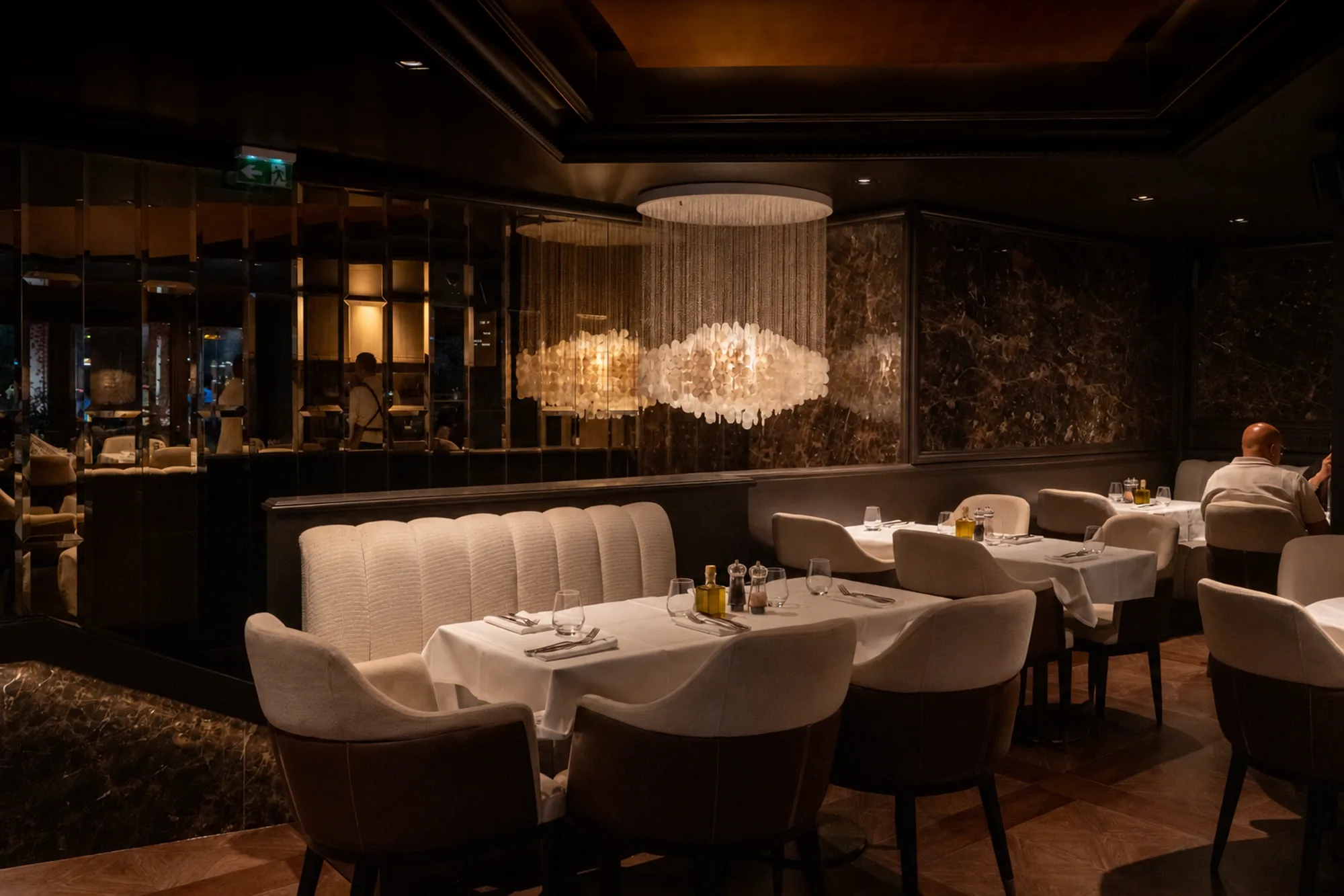 Salle du restaurant le soir, banquettes et lustre en nacre