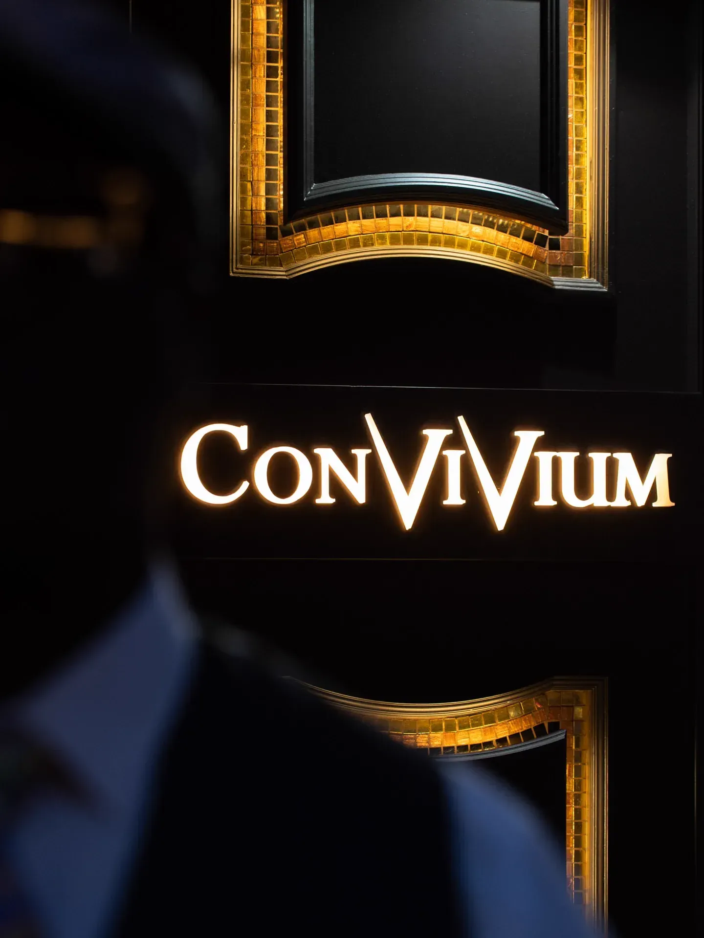 Illuminated Gran Caffè Convivium sign at dusk